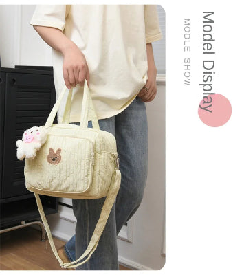 sac à langer jaune avec pendentif ourson dans la main attaches